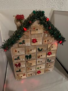 a house made out of wooden boxes with christmas decorations on top and numbers in the middle