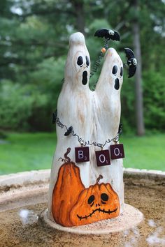 two fake ghost hands holding pumpkins on top of a stone bowl in front of trees