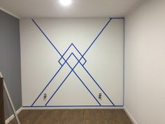 an empty room with blue lines painted on the wall and wood flooring in front of it