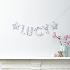 a white mantle with pink flowers and a blue teddy bear on it next to a sign that says juicy