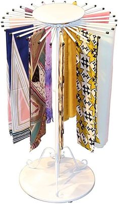 a rack with several different colored scarves hanging on it's sides and two white stands