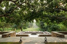 an outdoor seating area with stone benches and fire pit surrounded by trees in the background