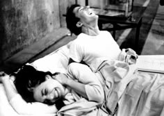 a woman laying on top of a bed next to a man with his eyes closed