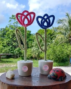 two cups with flowers in them sitting on a tree stump next to a toy car