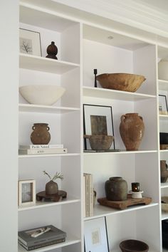 the shelves are filled with vases, bowls and other decorative items in white painted walls