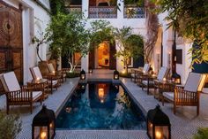 an indoor swimming pool surrounded by wooden chairs and tables with lit candles in the middle