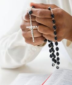 a person holding a rosary with a cross on it's arm and wearing a white shirt