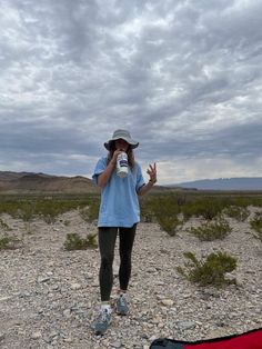 a woman taking a selfie in the desert with her camera and hat over her head