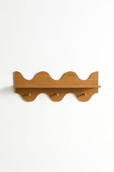 a wooden shelf mounted to the side of a wall with two coat hooks on it