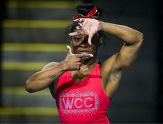 a woman in a red tank top is holding her hand up to her face and pointing at the camera