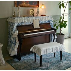 a piano in a living room with a bench and potted plant next to it