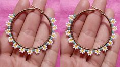 two small white and yellow beaded hoop earrings in gold tone setting on a pink background