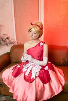 a woman in a pink and red dress sitting on a couch