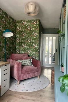 a living room with green wallpaper and pink chair in the middle of the room