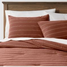 a bed with brown and white striped comforter on it's side, next to a wooden headboard