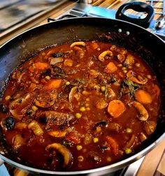 a pot filled with stew sitting on top of a stove next to a wooden table