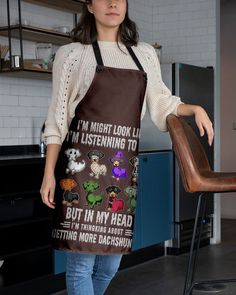 a woman standing next to a wooden chair wearing an apron with images of monsters on it