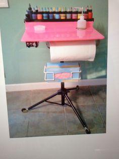 a pink table with several rolls of toilet paper sitting on it's top and two roll holders in front of it