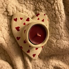 a heart shaped tea light holder with a candle in it on top of a blanket