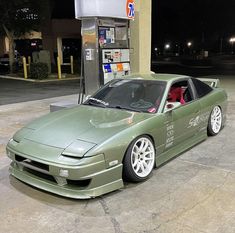 a green sports car parked in front of a gas pump at an empty gas station