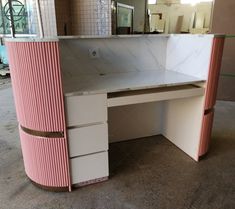 a pink and white desk in a room with mirrors on the wall behind it,