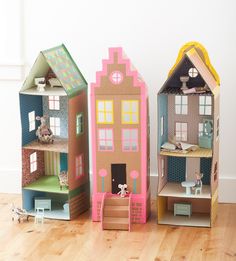 three wooden doll houses with windows and doors on the front, one has a cat in it