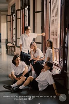 a group of young people sitting on the floor in front of a window with their arms around each other