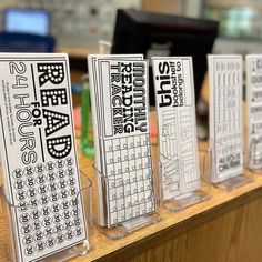 four clear plastic stands with black and white text on them in front of a computer desk