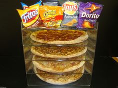 a stack of pizzas sitting on top of a counter next to chips and drinks