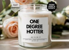 a white candle with the words one degree hotter on it next to some flowers