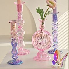 three glass vases with flowers in them sitting on a table next to each other