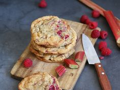 raspberry chocolate chip cookies on a cutting board with a knife and strawberries