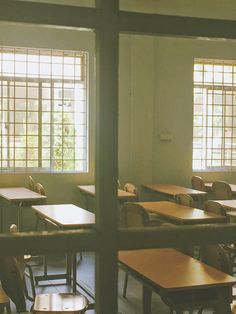 an empty classroom with wooden desks and windows