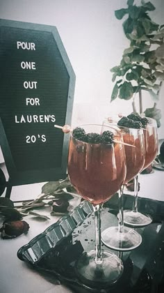 three glasses filled with liquid sitting on top of a table next to a sign that reads four one out for lauren's 20's