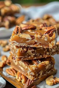 three pieces of pecan bar stacked on top of each other with nuts in the background