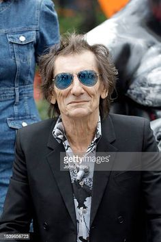 an older man wearing sunglasses sitting in front of a motorbike on the street