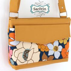 an orange and blue flowered purse hanging on a wall with the name sacotin printed on it