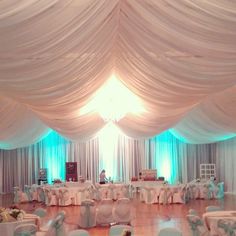 a banquet hall with tables and chairs covered in white draping