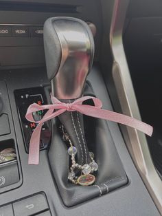 a car dashboard with a pink ribbon tied around the steering wheel and beads on it