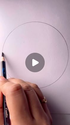 someone is drawing a circle on paper with a marker and pencil in front of them