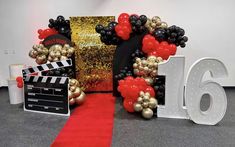 a red carpeted room with balloons and decorations on the floor, along with a sign that says 16