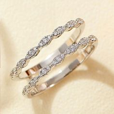 two white gold wedding rings with diamonds on top and in the middle, sitting next to each other