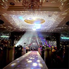 a large room filled with lots of lights and people standing on the side of it