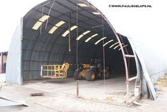 a large metal structure with two tractors in it