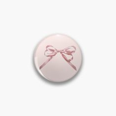 a pink button with a bow on it's side, against a white background