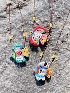 three colorful toys are hanging from strings on a rock surface with rocks in the background