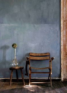 a chair and vase sitting next to each other in front of a wall with blue paint