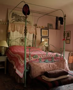 a bedroom with pink walls and an iron bed frame in the middle, along with pictures on the wall