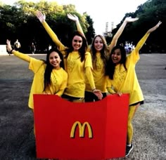 four girls in yellow shirts are holding up a mcdonald's sign