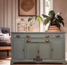 a green cabinet with gold handles and drawers in a living room next to a birdcage